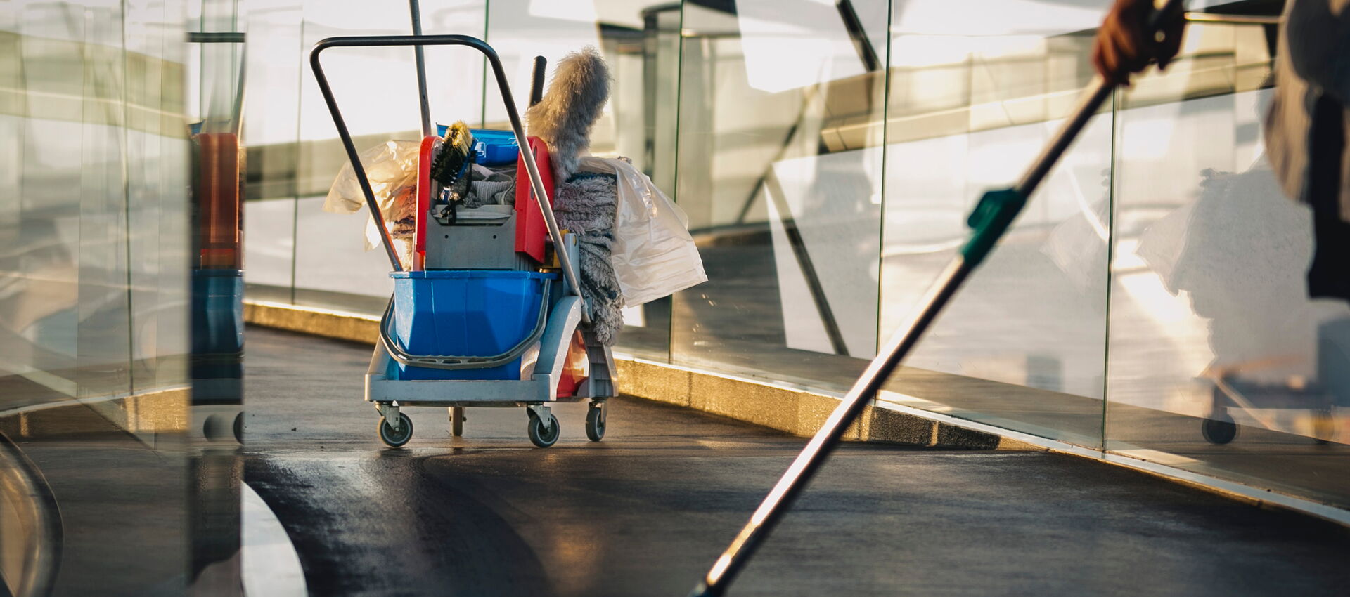 Mitarbeiterin reinigt Büroraum mit Wischer – Unterhaltsreinigung Hof